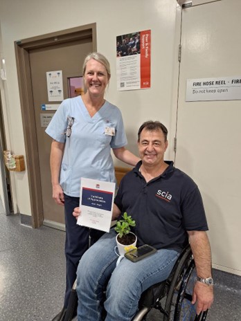 Jason Wright in a wheelchair with a nurse standing behind him